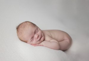 natural newborn baby photography cream curled pose smile wind
